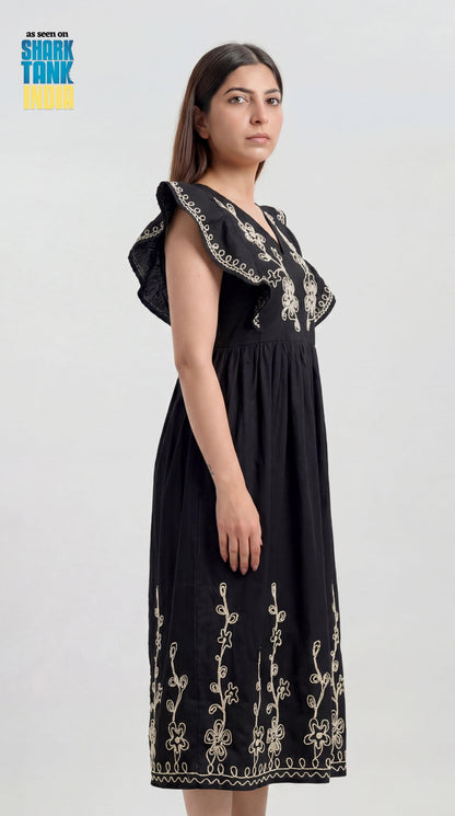 Woman wearing a black dress with floral embroidery on a white background