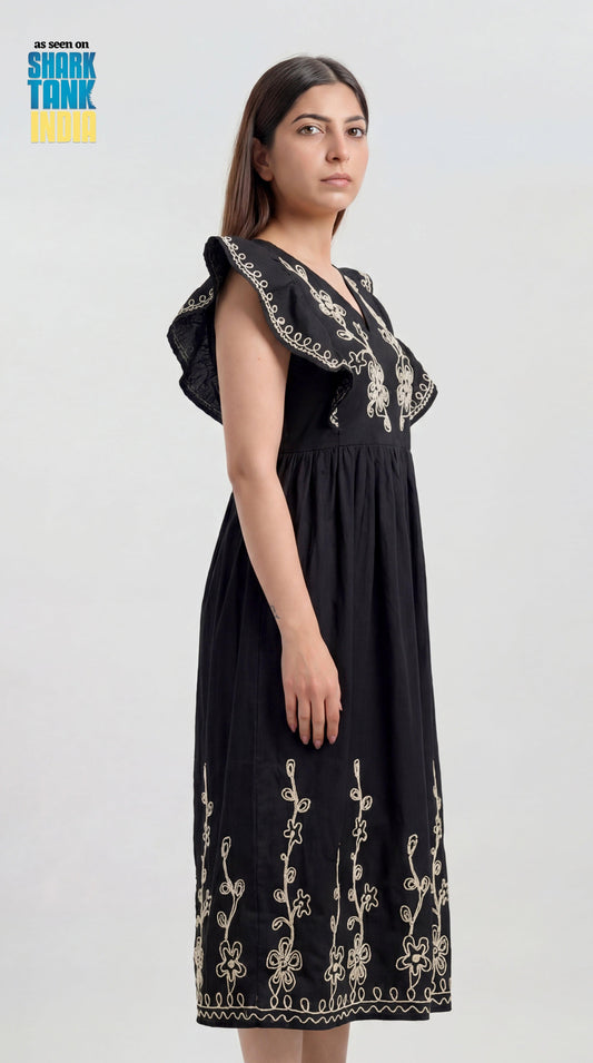 Woman wearing a black dress with floral embroidery on a white background