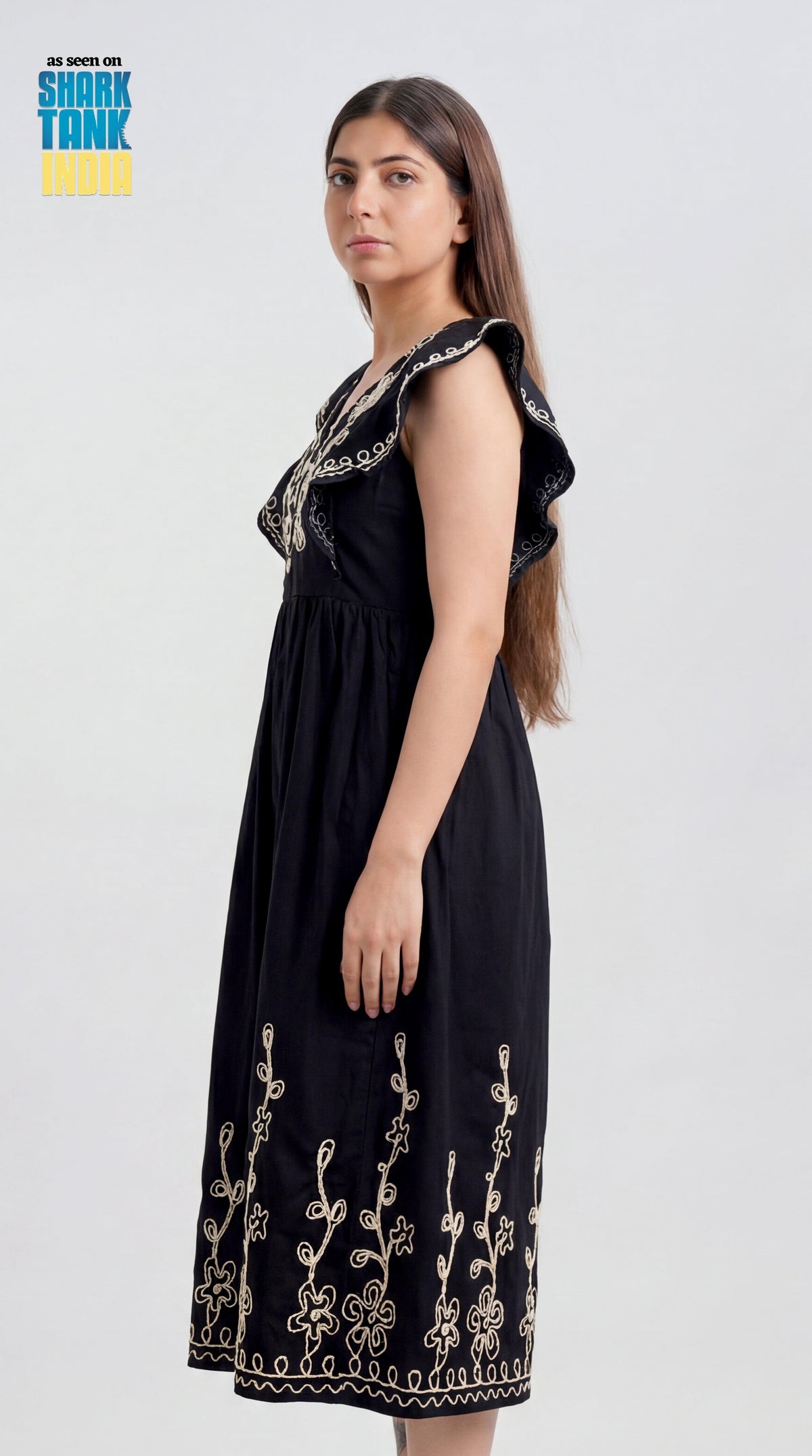 Woman wearing a black dress with floral embroidery on a white background