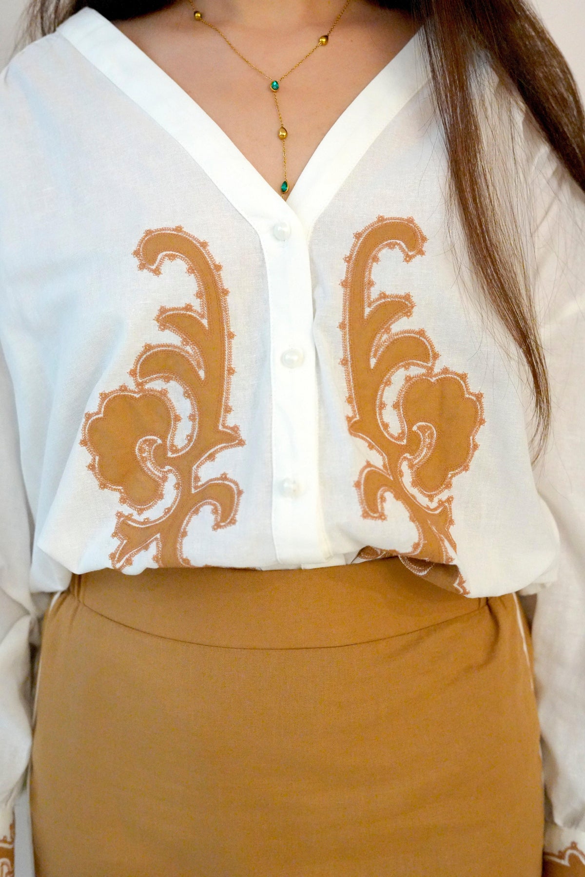 White blouse with brown embroidery and a person wearing it